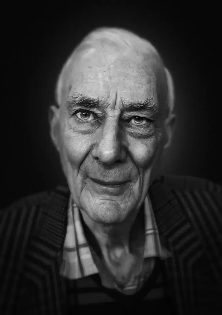 Black and white portrait of an elderly man with expressive eyes, deep lines on his face, and a calm, reflective expression