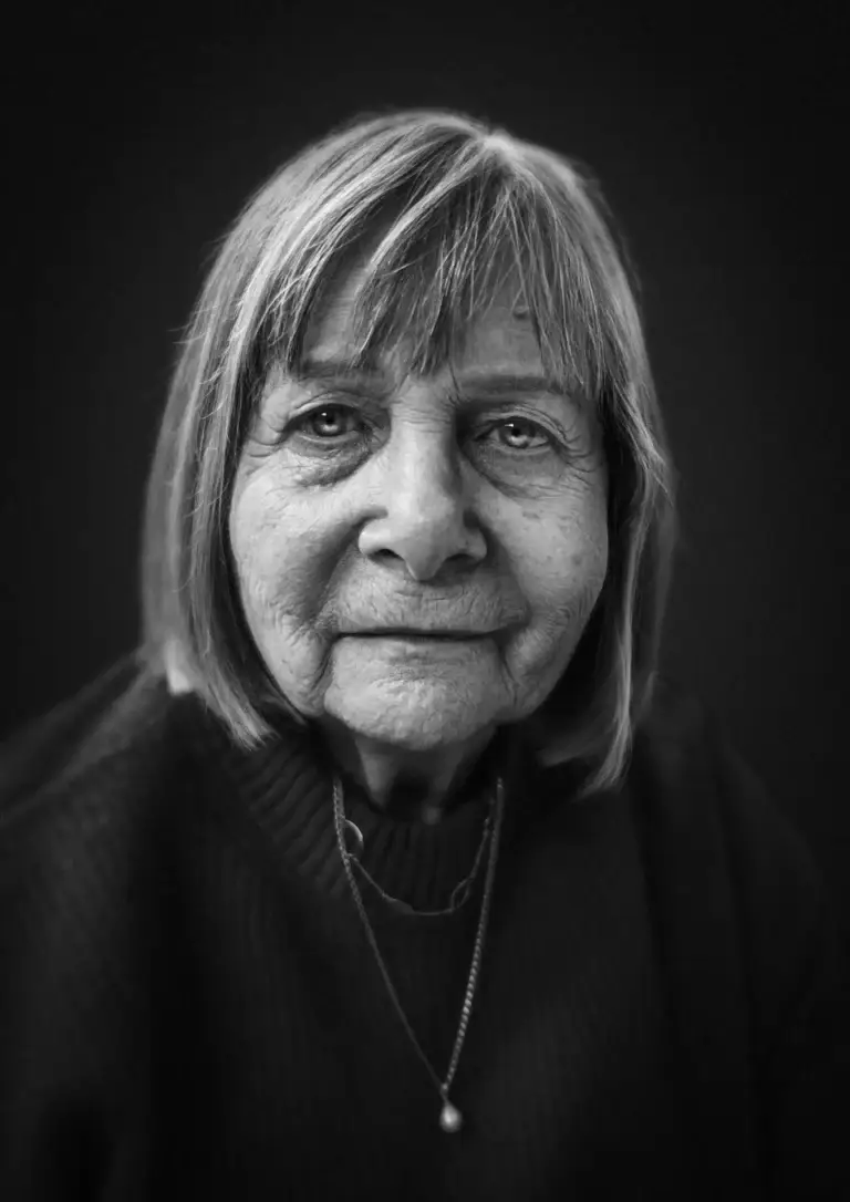 Black and white portrait of an elderly woman with straight hair and a dark jumper, looking softly into the camera