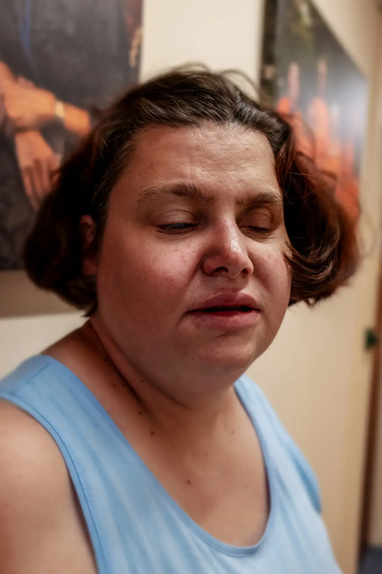 Portrait of a blind woman in a blue top indoors.