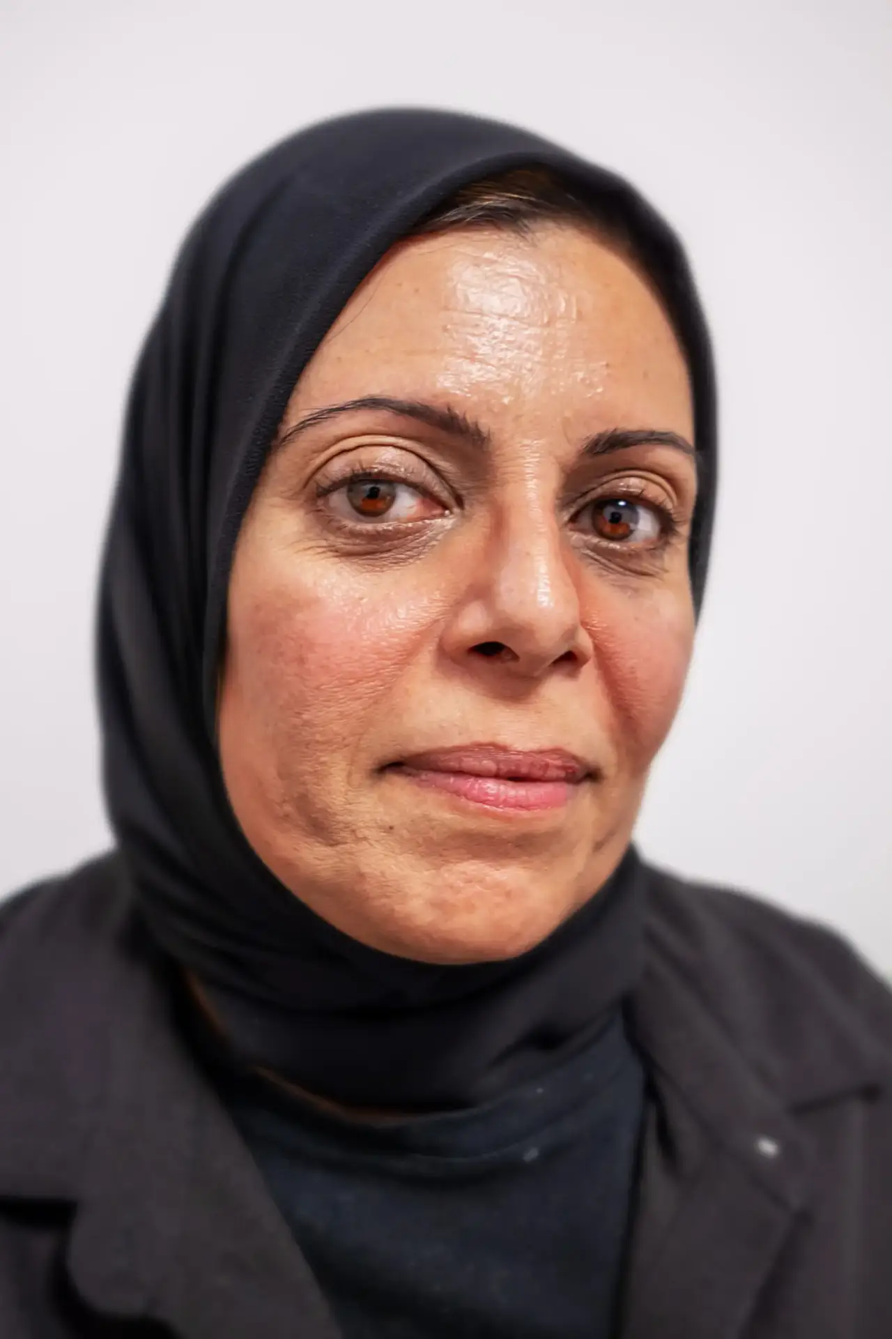Woman wearing a black headscarf looking calmly at the camera.