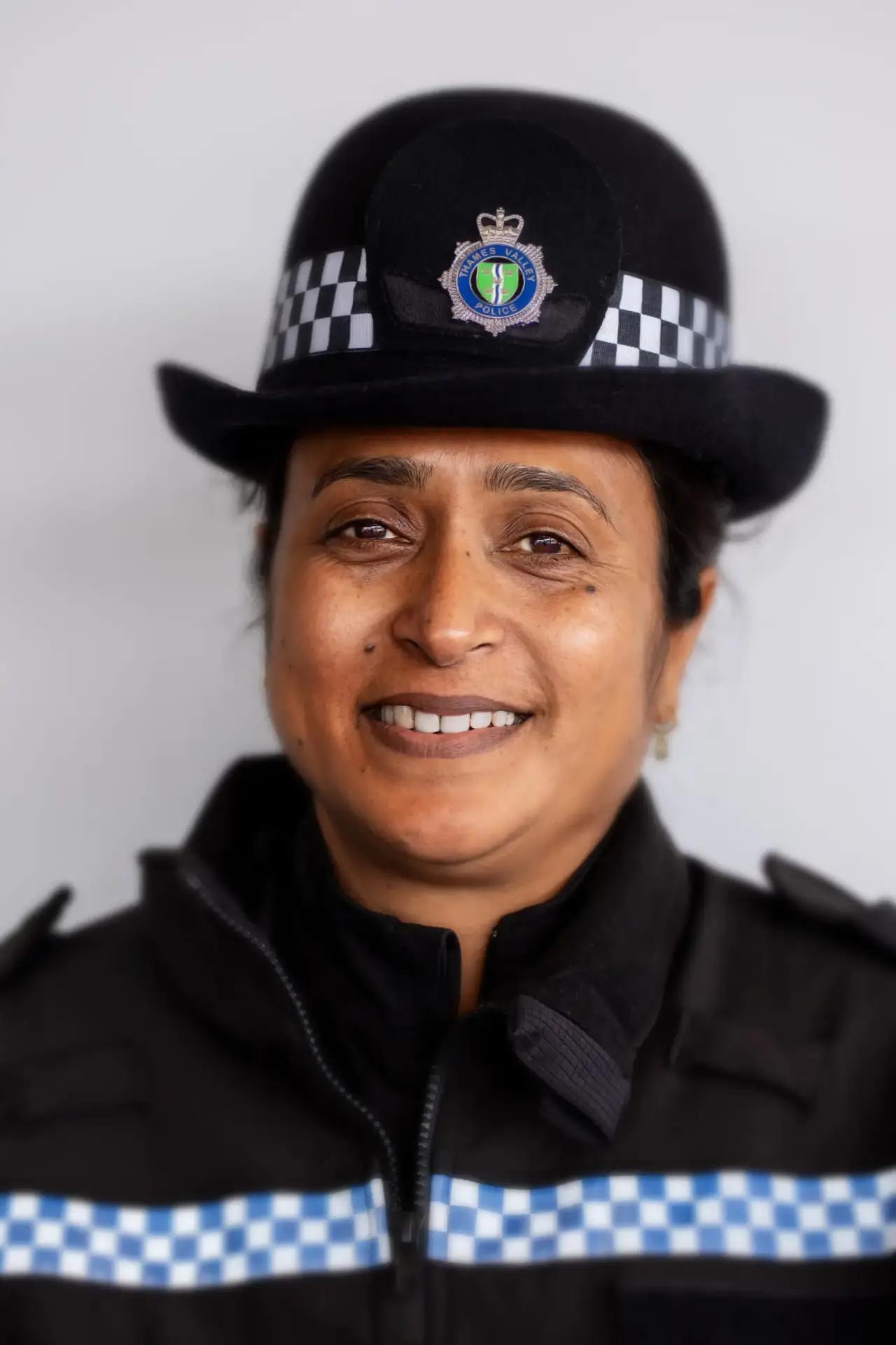 Smiling police officer in Thames Valley Police uniform with checked hat band