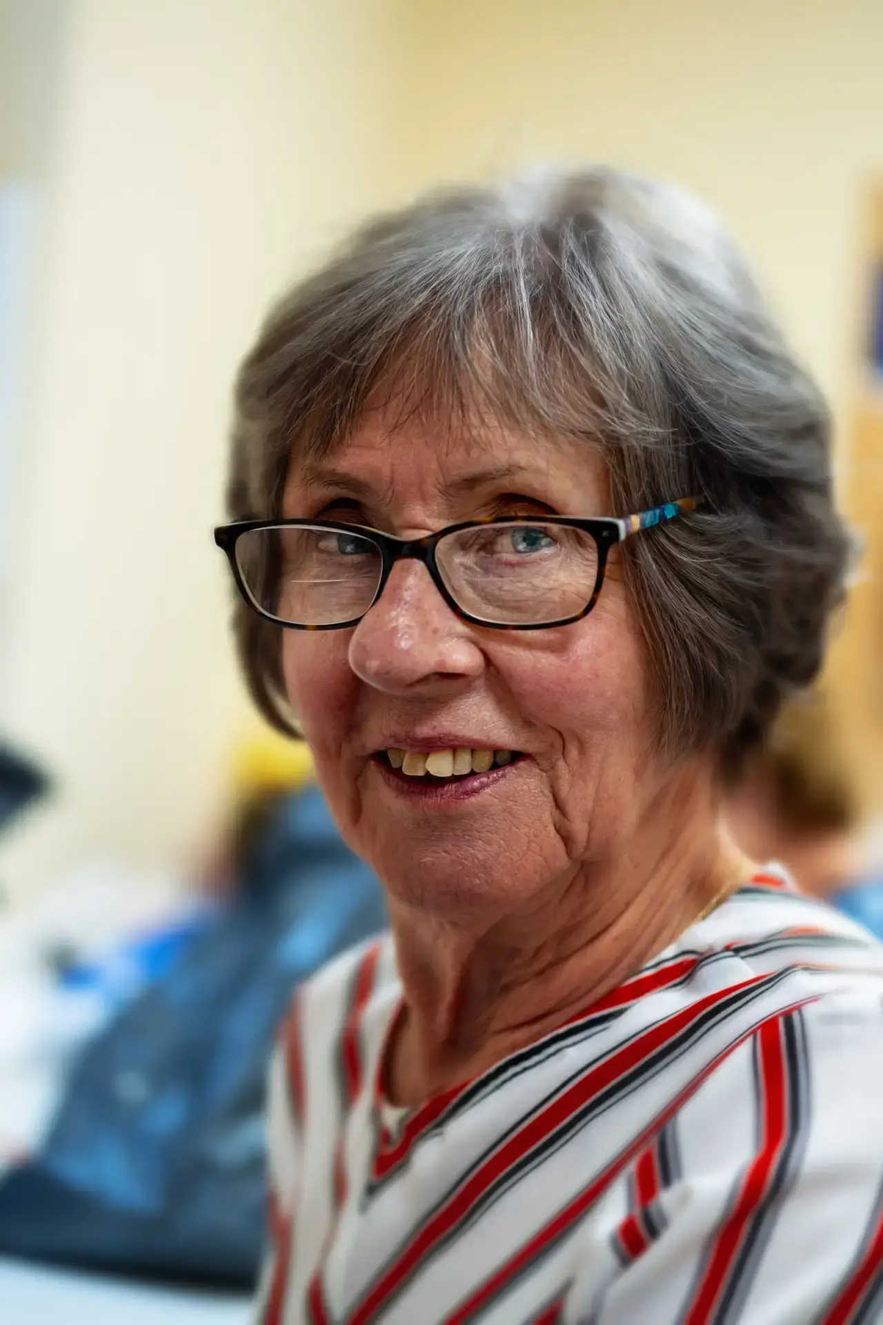 Smiling older woman with glasses wearing a striped top
