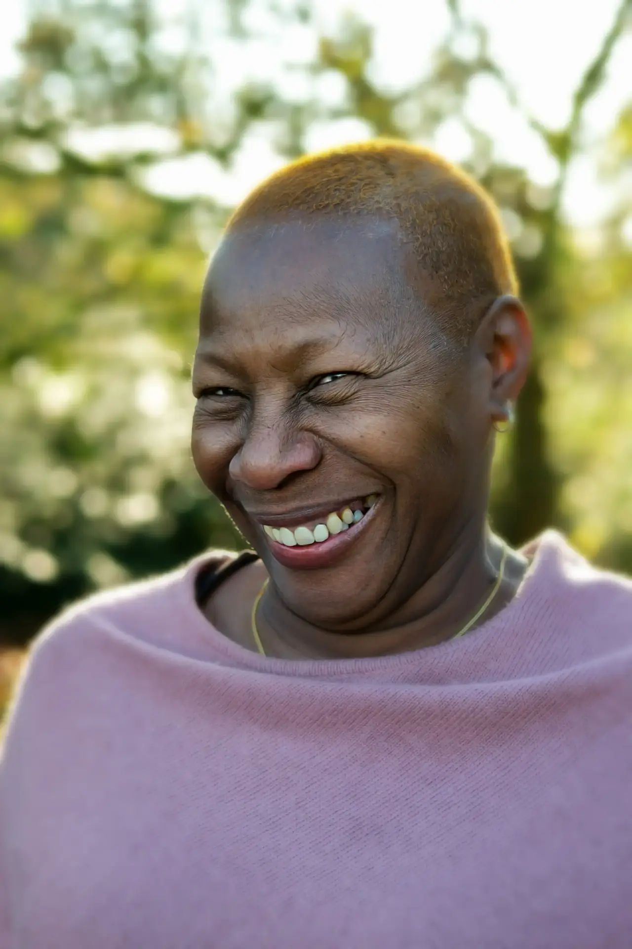 volunteering 8 Smiling woman with short hair wearing a pink top outdoors in soft sunlight