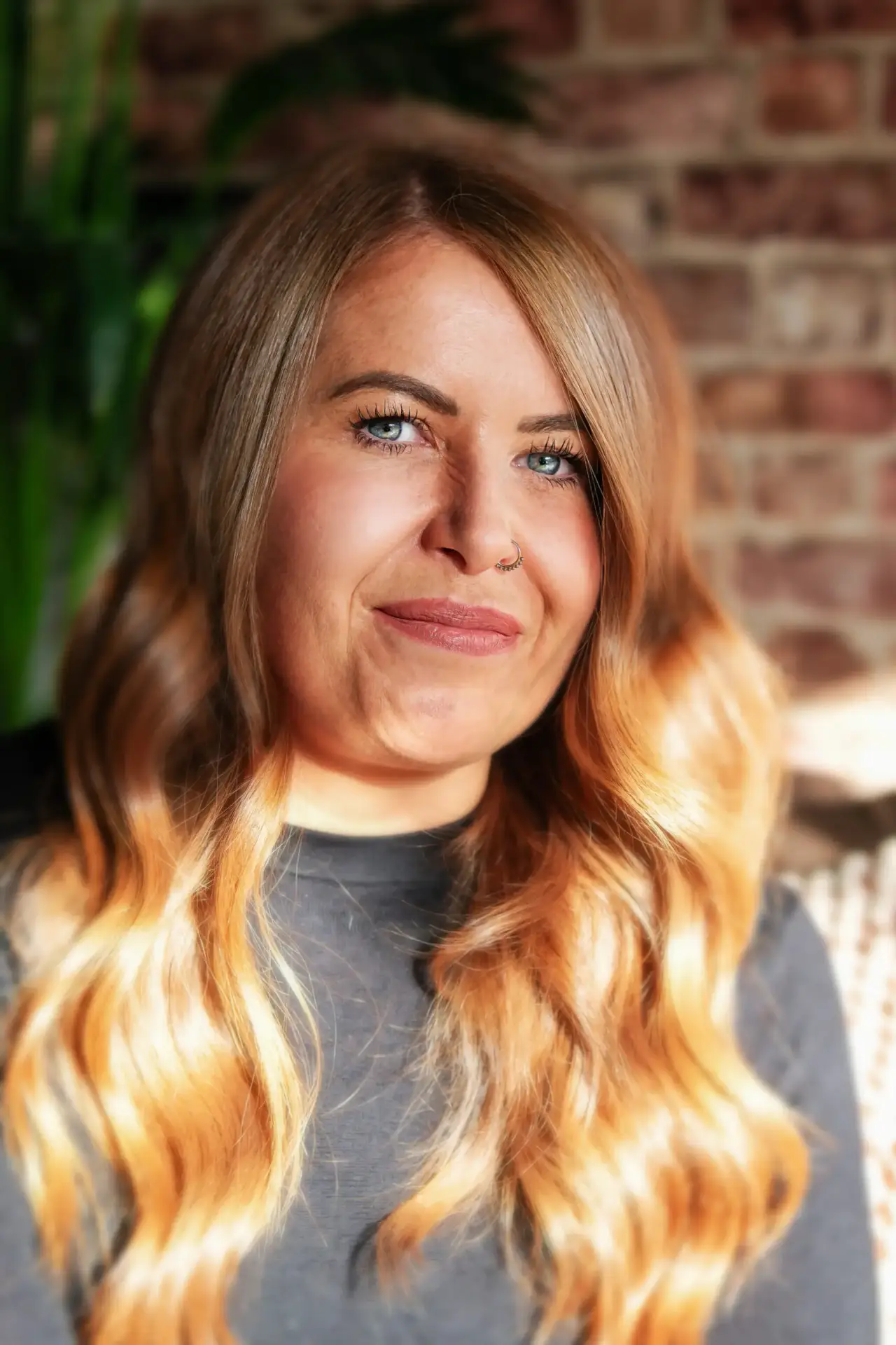 volunteering 7 Smiling woman with long wavy blonde hair and a nose ring wearing a black top indoors