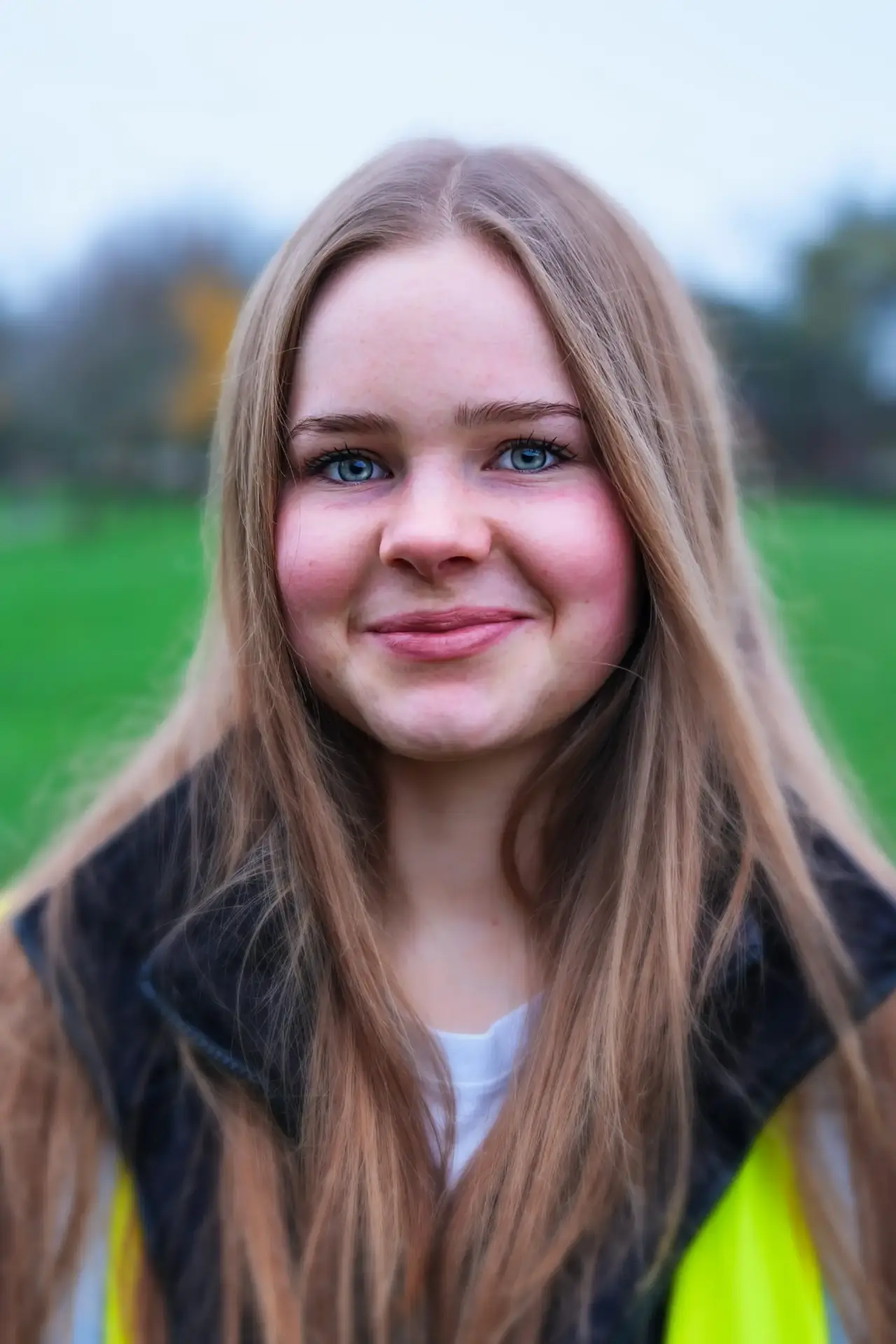 volunteering 5 Smiling teenage girl with long hair wearing a high-vis vest outdoors