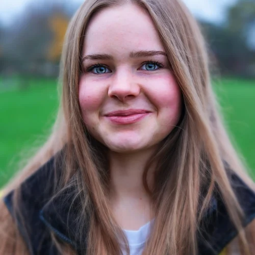 Smiling teenage girl with long hair wearing a high-vis vest outdoors