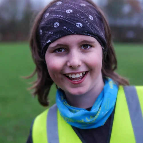 Smiling child wearing a high-vis vest and headband outdoors